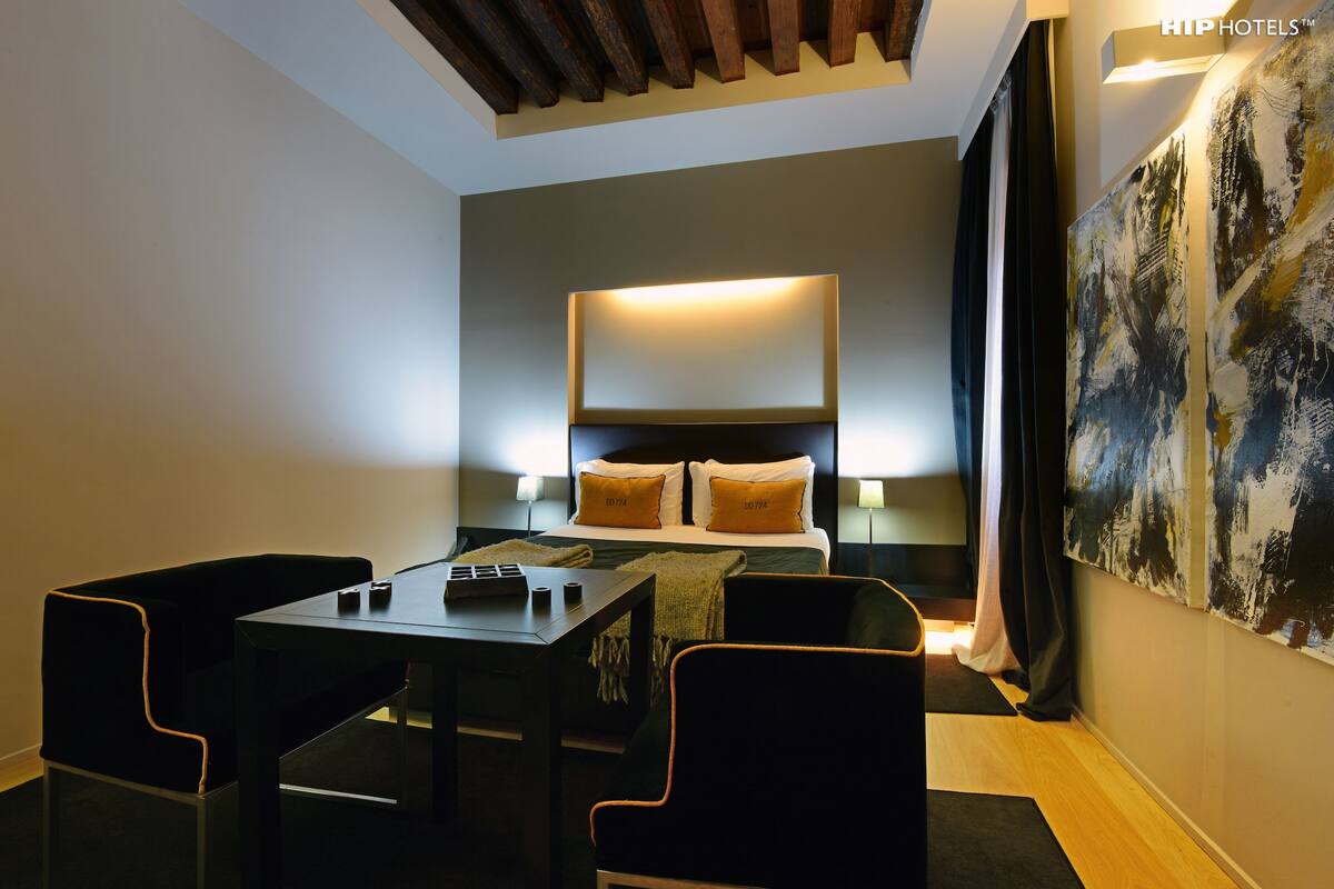 Ein Hotelzimmer mit Bett, Nachttischen, einem Schreibtisch und Stühlen.