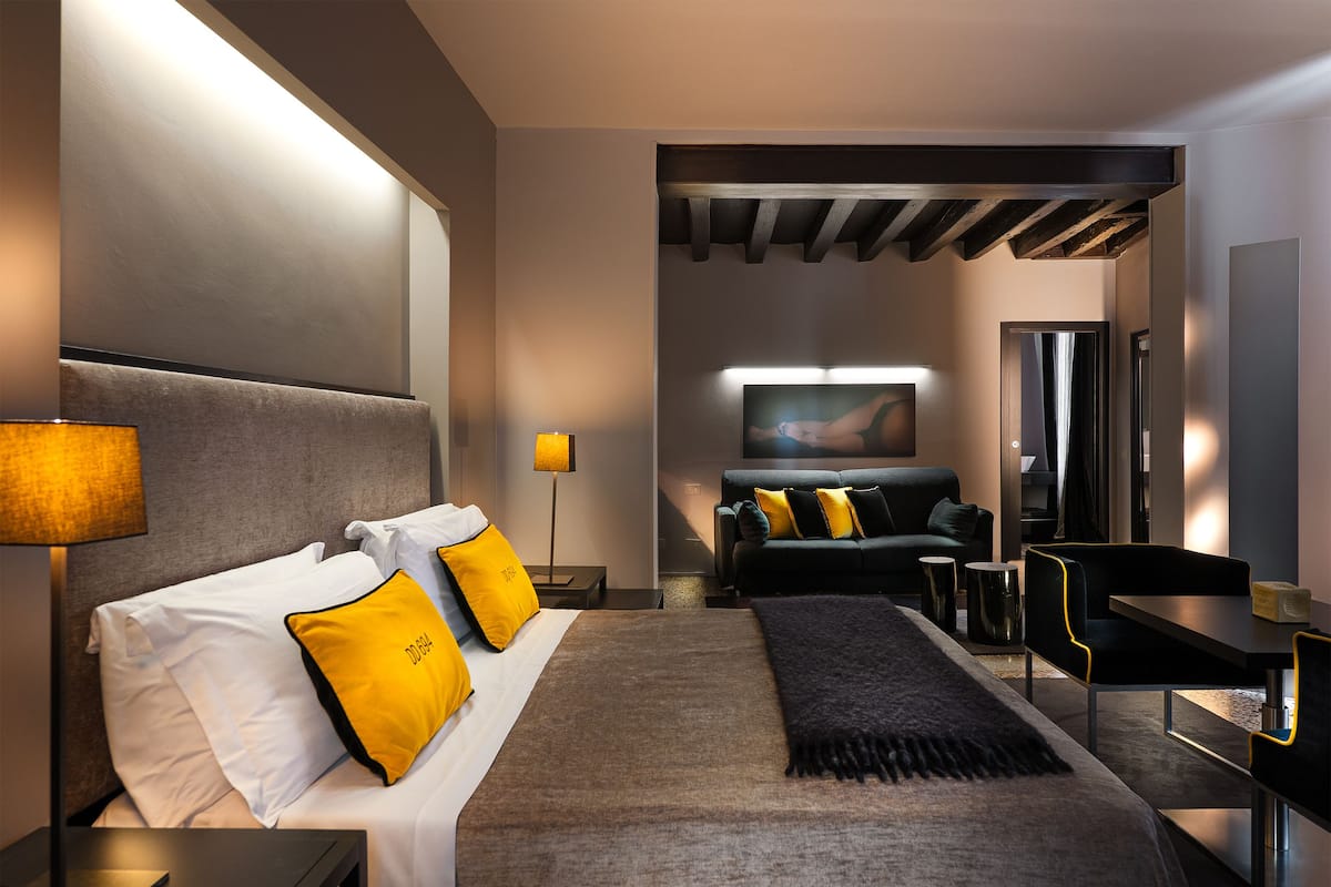 Ein modernes Hotelzimmer mit einem großen Bett, einer Sitzecke, einem Schreibtisch und einem Flachbildfernseher.