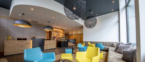 A modern lounge area with a curved ceiling, seating arrangements, and a bar area in the background.