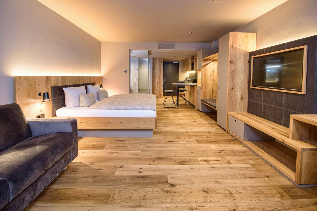 Une chambre moderne avec un grand lit, un canapé, un bureau et une télévision.