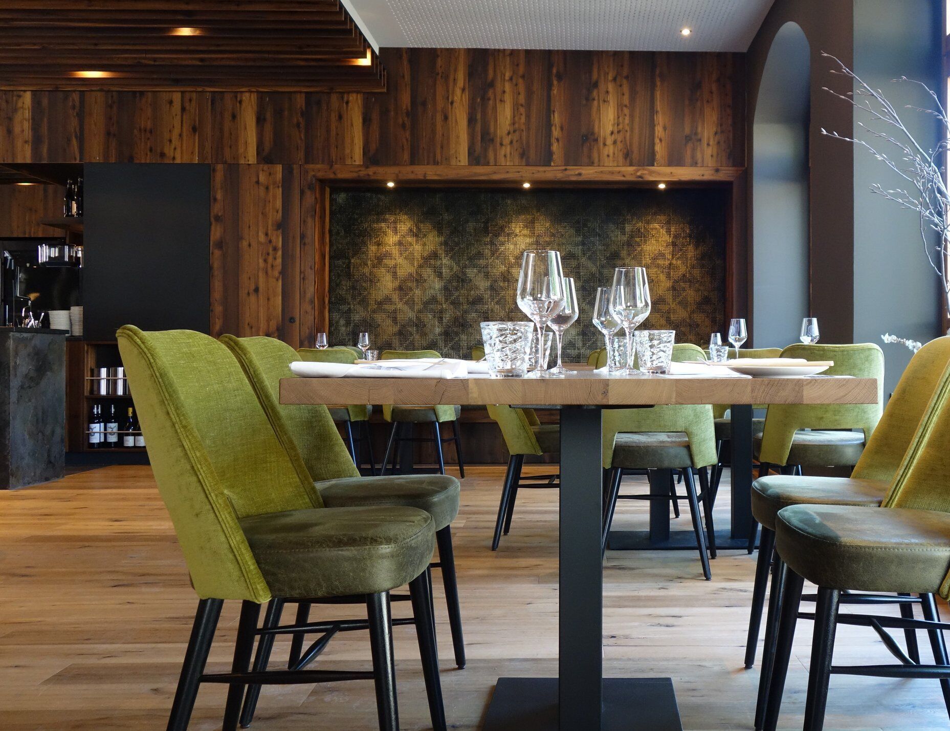 Un comedor con una mesa de madera dispuesta para seis personas, rodeado de sillas tapizadas de color verde.