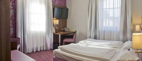 Une chambre d’hôtel avec un grand lit, un bureau équipé d’un ordinateur, une chaise et un téléphone.