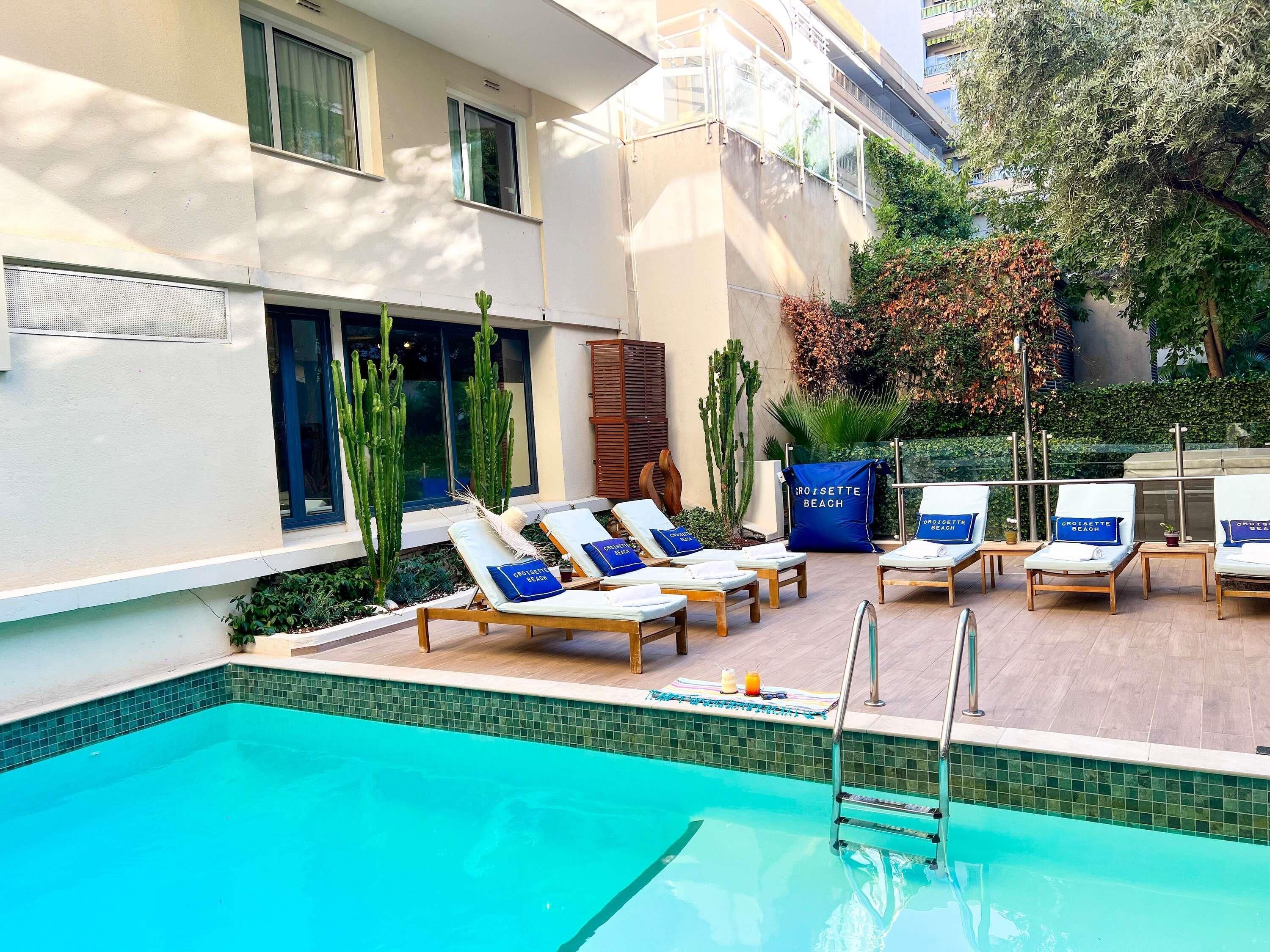 Una piscina al aire libre, sombrillas, sillones reclinables de piscina