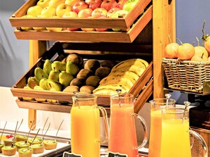 Een ontbijtbuffet met verschillende soorten fruit, een rieten mand en diverse vruchtensappen.