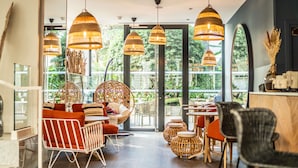 Een modern interieur met rieten meubels, grote ramen en hangende pendantlampen.