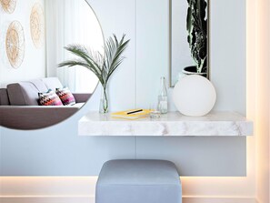 Een moderne woonkamer met een bank, een salontafel, een vaas met planten, een fles, glaasjes en een rond wit voorwerp.
