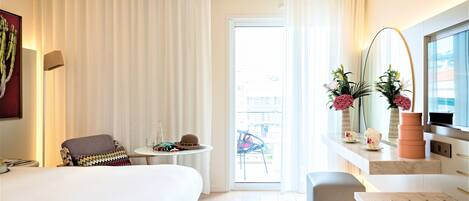 Une chambre d’hôtel avec un lit, une chaise, une petite table, une télévision et un balcon avec vue.