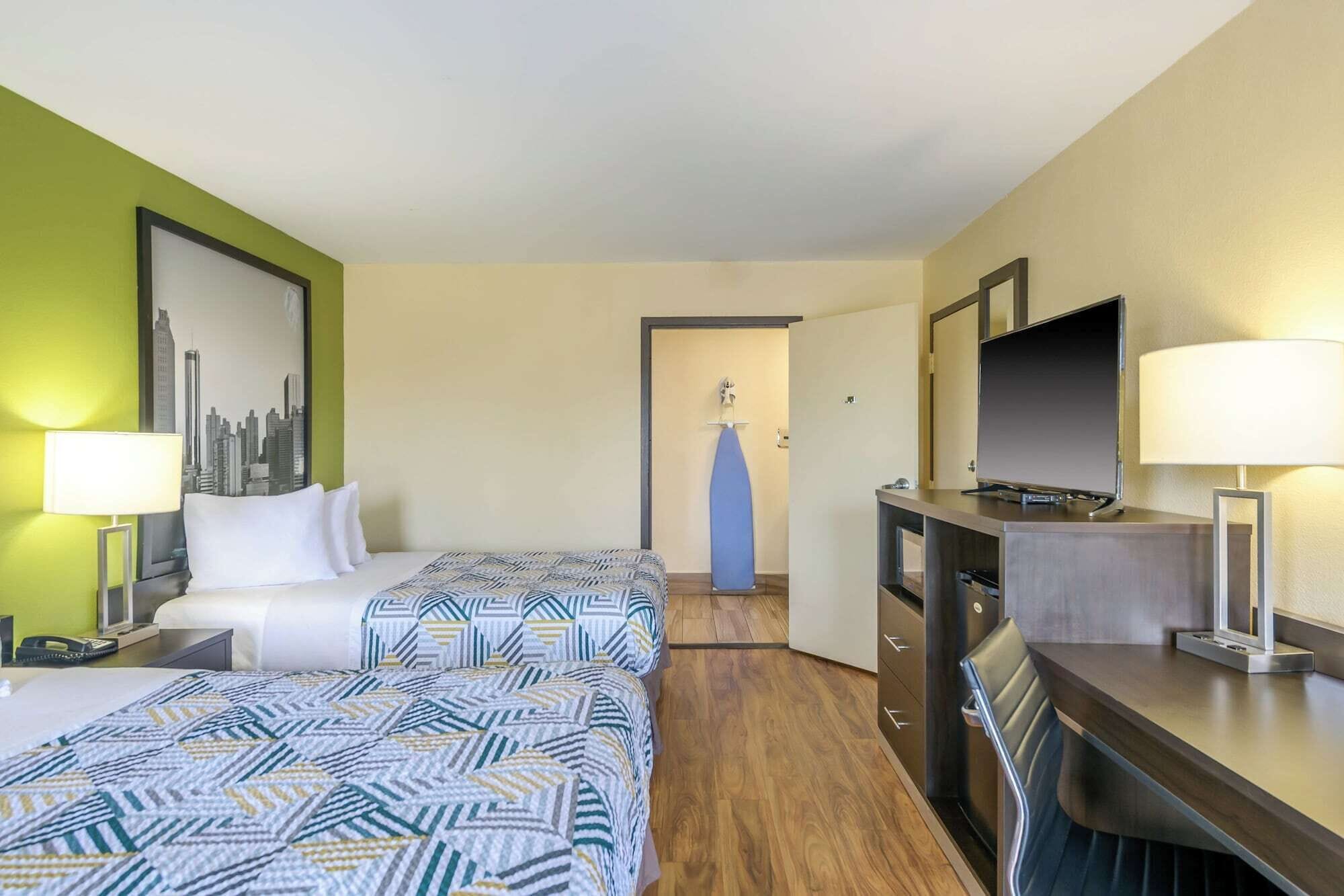 Une chambre d’hôtel avec un lit, un bureau, une télévision et un miroir.
