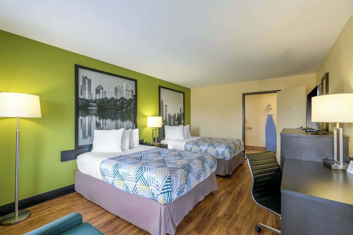 A hotel room with two beds, green walls, and a cityscape painting.