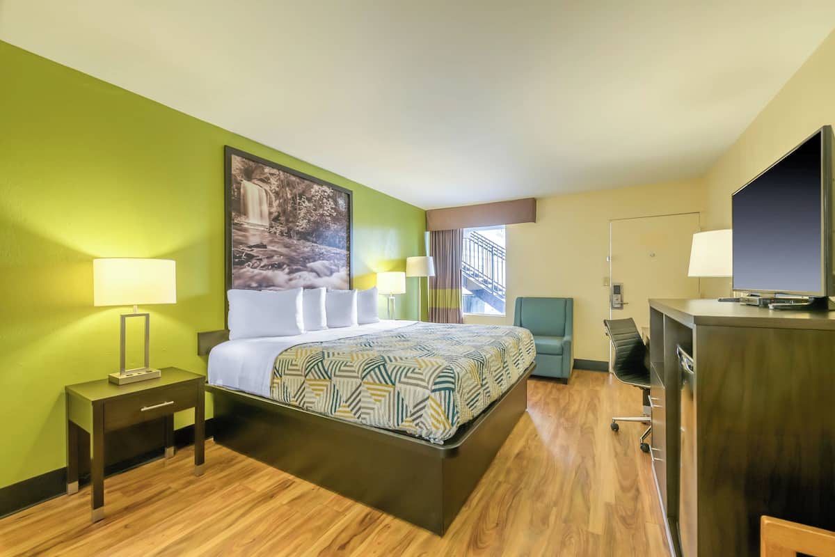 A hotel room with a large bed, a desk with a computer, a TV, and a window with a view of a bridge.