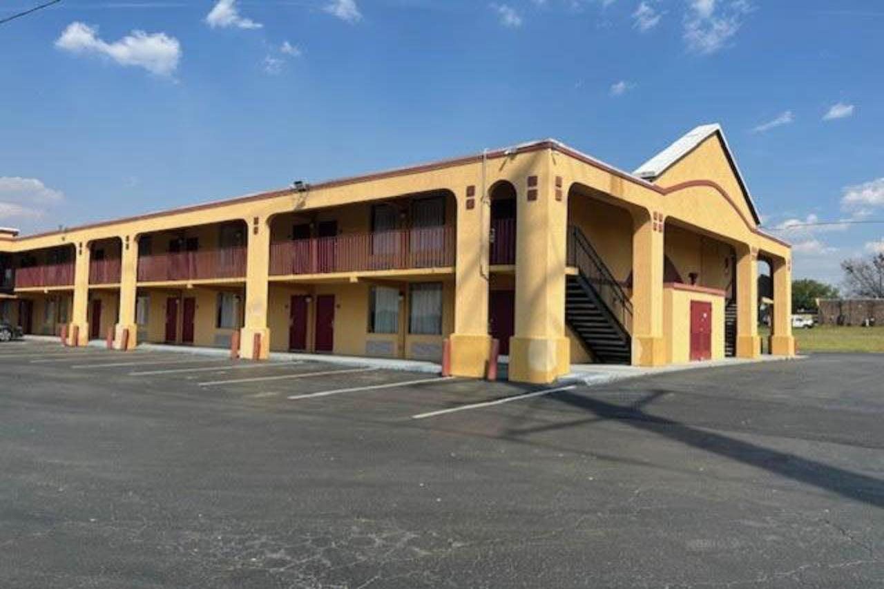 A multi-story motel with a central staircase, multiple balconies, and a parking lot.