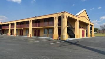 A multi-story motel with a central staircase, multiple balconies, and a parking lot.