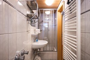 A modern bathroom with a shower enclosure, a sink, and a towel rack.