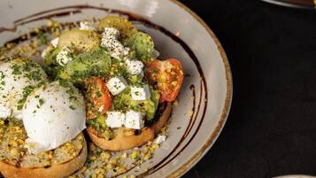 Ein Teller Bruschetta mit Guacamole, Tomaten und Käse, dazu eine Tasse Kaffee.