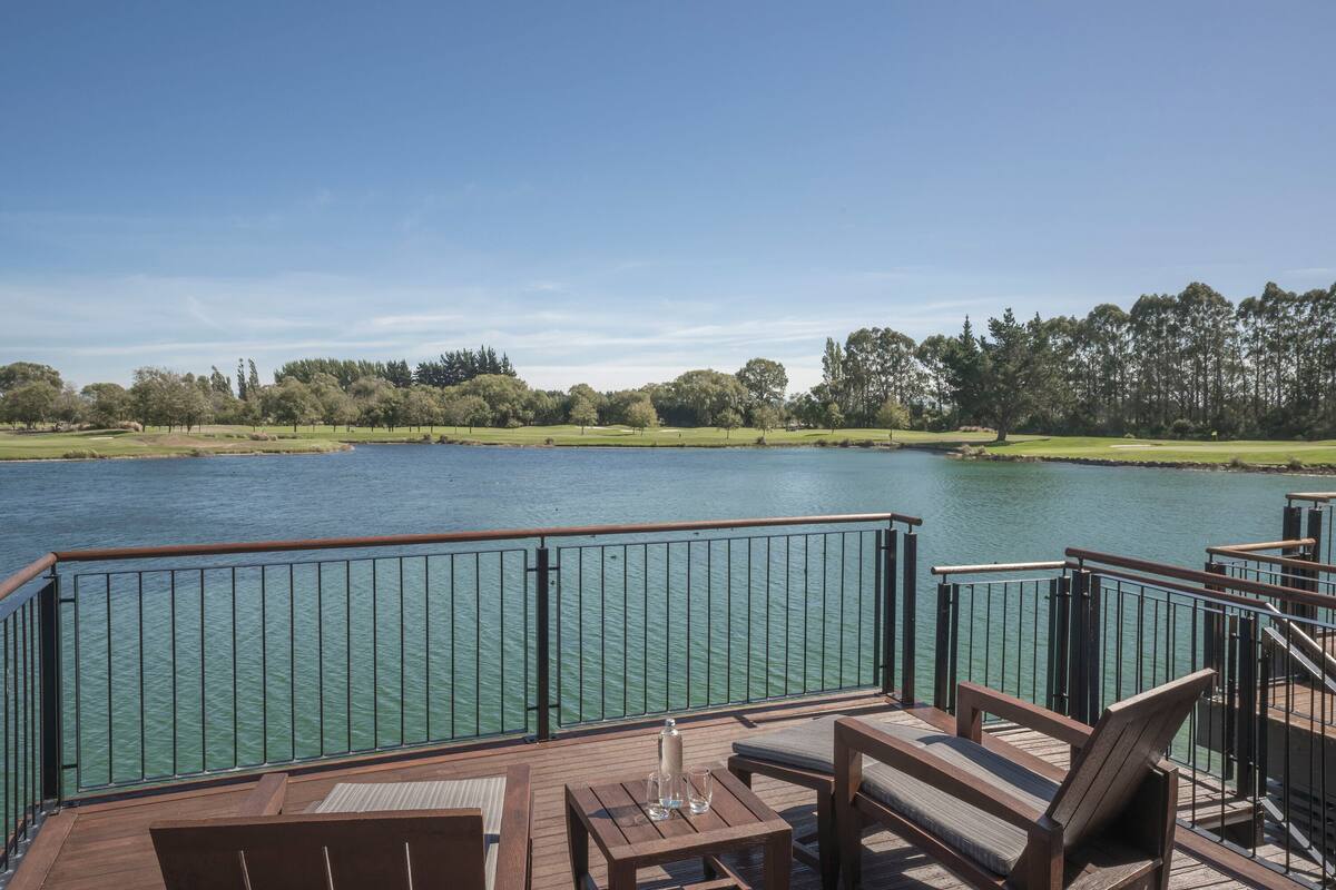 A wooden deck with outdoor seating and a view of a lake.