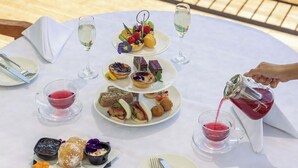 A table set for a meal with various dishes and drinks, overlooking a body of water.
