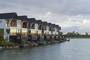 Una hilera de casas modernas frente al agua con balcones, conectadas por un muelle.