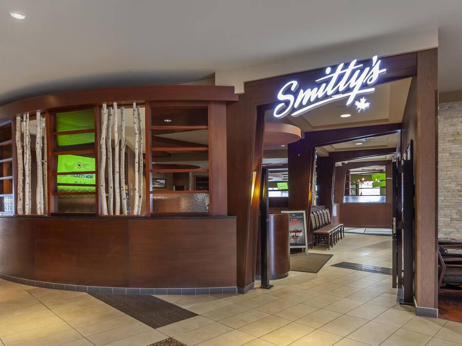 A hotel lobby with a reception desk, a sign for 'Smithy's', and a seating area with benches.