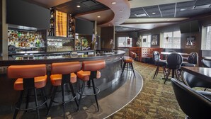 A bar area with a curved counter, multiple stools, and a variety of bottles and glasses. - Best Western Cold Lake Inn (Cold Lake)