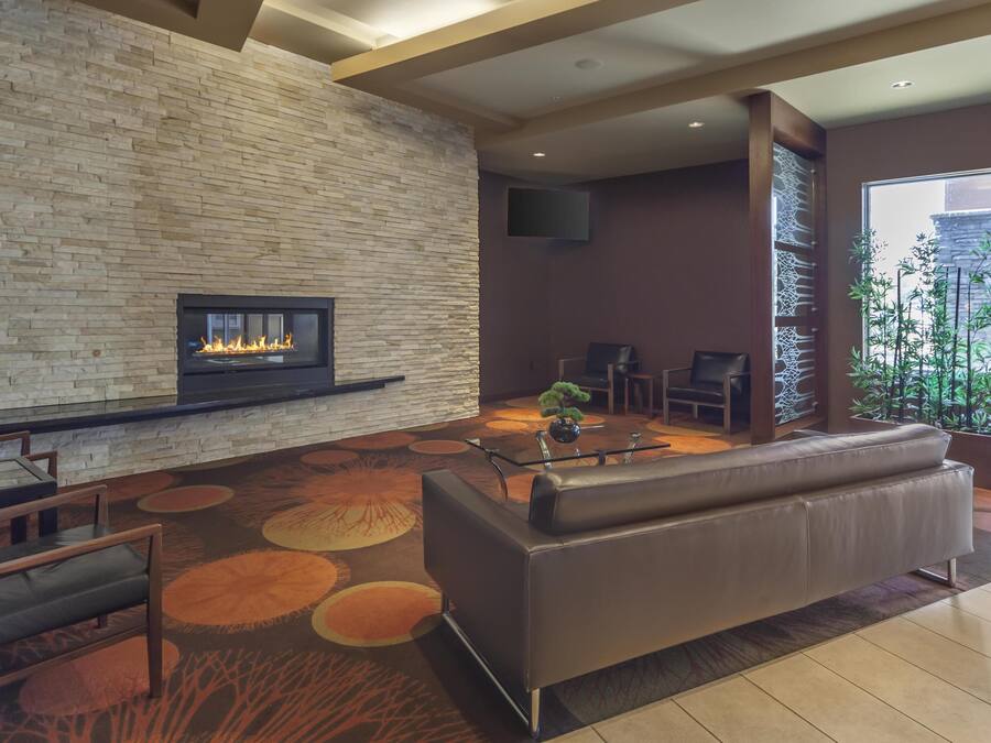 A modern lobby with a stone wall, a fireplace, leather seating, and a large window.