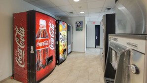 A hallway with vending machines, including Coca-Cola and other beverages, and an ice cube dispenser. - Motel 6 Brampton, ON - Toronto (Brampton)