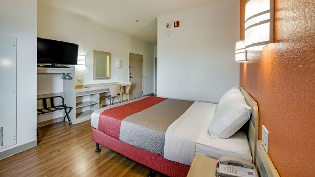 A hotel room with a bed, desk, and TV. - Motel 6 Brampton, ON - Toronto (Brampton)