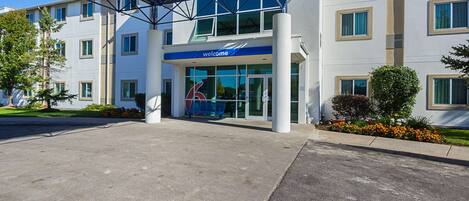 A modern building with a 'Welcome' sign, large windows, and a covered entrance area.