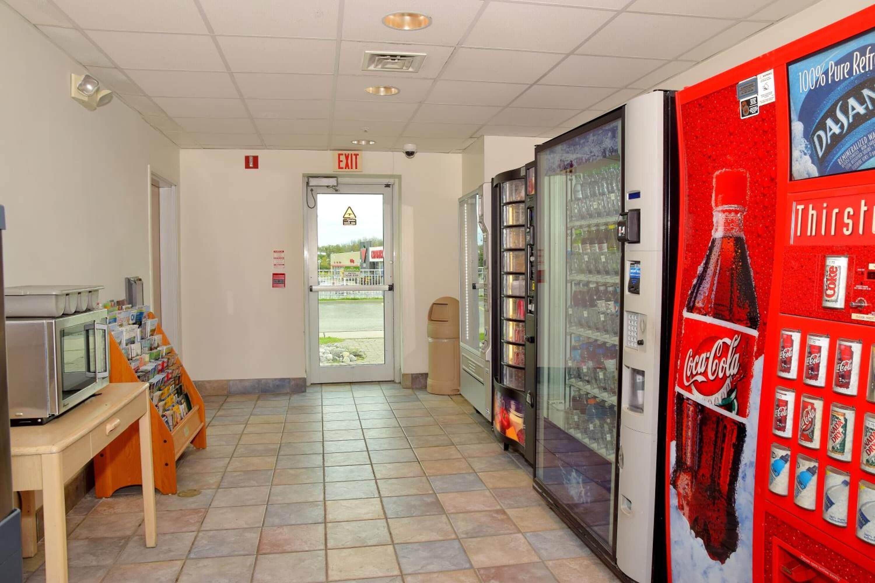 A hallway with a vending machine, a microwave, and a display of magazines.