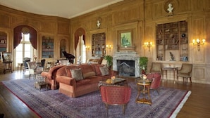 A spacious library with a fireplace, bookshelves, and comfortable seating areas. - Oheka Castle Hotel & Estate (Huntington)