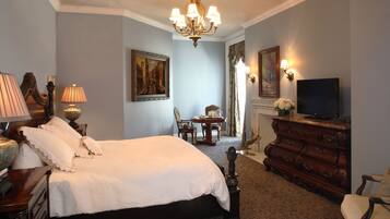 A hotel room with a large bed, a dresser, a television, and a chandelier.