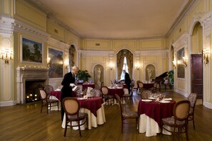 A formal dining room with multiple tables set for service, a fireplace, and classical architectural details. - Oheka Castle Hotel & Estate (Huntington)