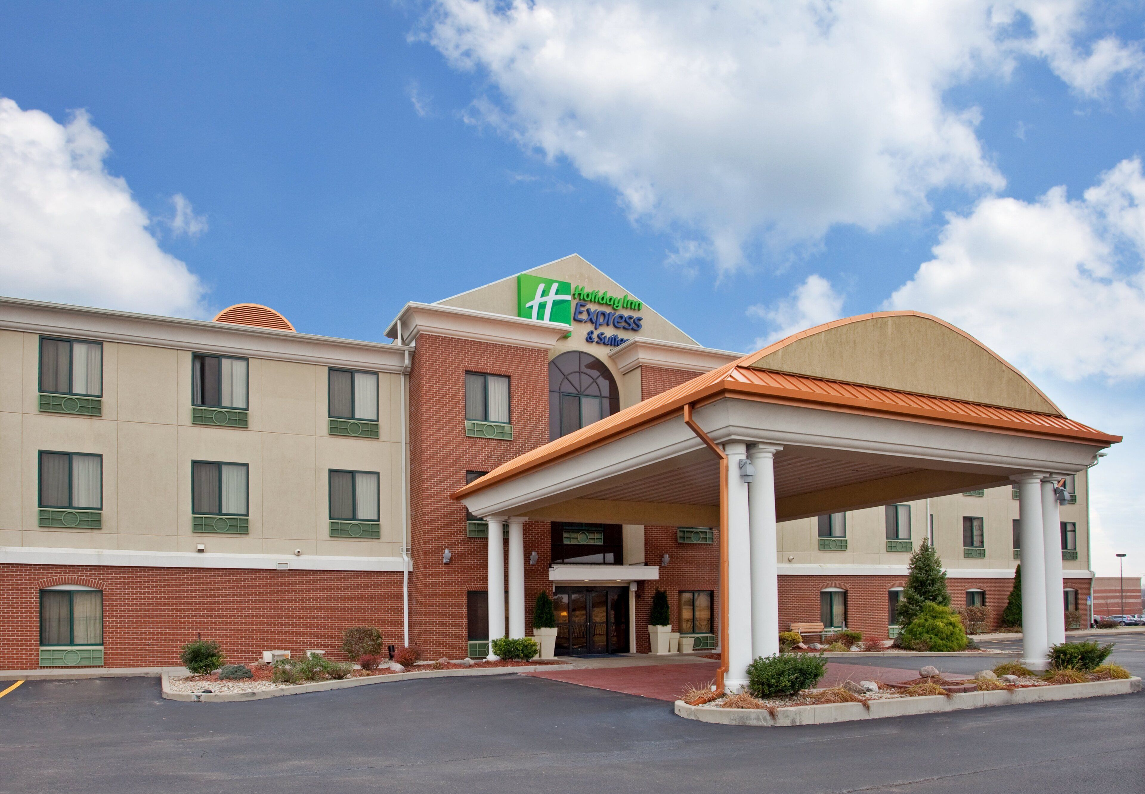 A Holiday Inn Express hotel with a brick facade, a covered entrance, and a clear sky.