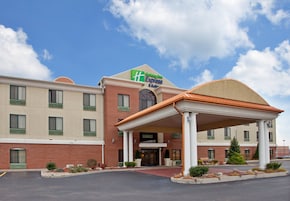 Un hotel Holiday Inn Express con fachada de ladrillo, un acceso cubierto y cielo despejado.