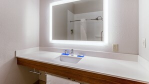 A bathroom with a white sink, a mirror with a light, and a towel hanging on a rack. - Holiday Inn Express & Suites O'Fallon/Shiloh by IHG (O'Fallon)