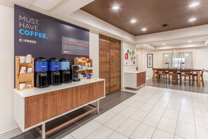 Una estación de café moderna con varias máquinas de café, una barra de madera y un área de comedor con mesa y sillas.