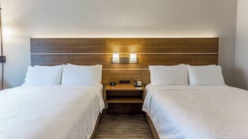 A hotel room with two beds, a wooden headboard, bedside lamps, and a nightstand with a phone.