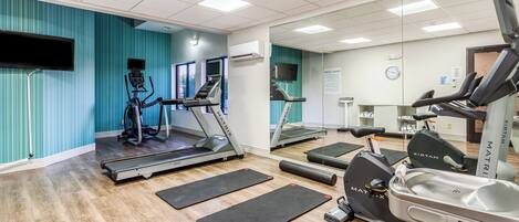 A fitness center with treadmills, exercise bikes, and mats.
