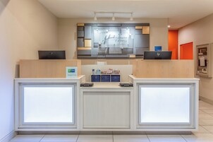 Un mostrador de recepción de hotel con diseño moderno, una pantalla digital y un cartel de Holiday Inn Express & Suites.