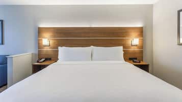 Ett hotellrum med en stor säng, två sängbord med lampor, en telefon och en digital klocka.