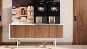 A coffee station with two coffee machines, a coffee grinder, and various coffee pods and cups. - Holiday Inn Express & Suites O'Fallon/Shiloh by IHG (O'Fallon)