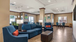 A spacious lobby with blue seating, a coffee table, and a dining area with a table and chairs.