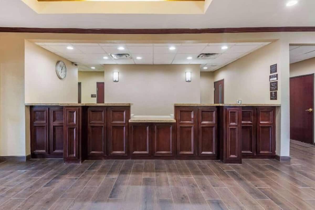 A reception area with a counter, wooden paneling, a clock, and a tiled floor.
