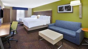 A hotel room with two beds, a sofa, a desk, and a television.