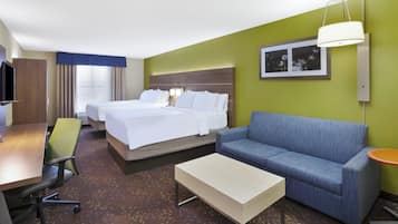 A hotel room with two beds, a sofa, a desk, and a chair.