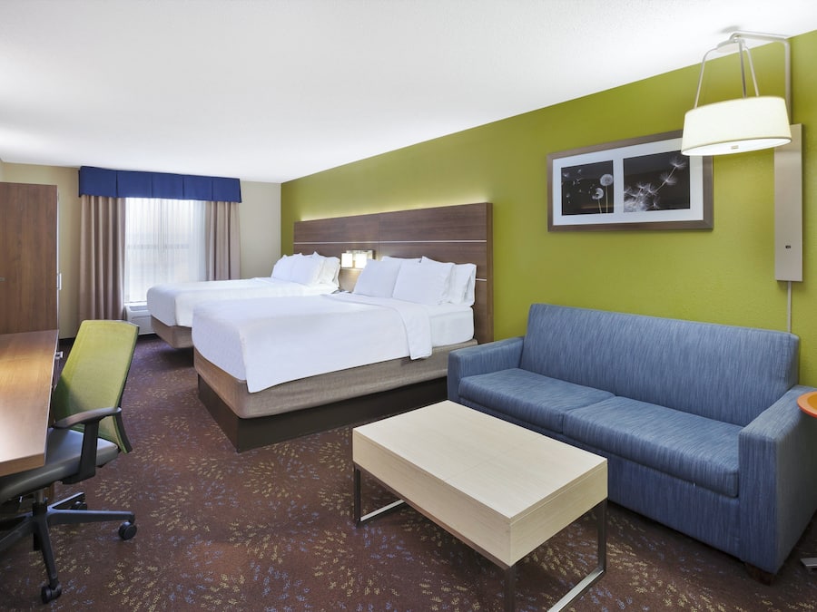 A hotel room with two beds, a sofa, a desk, and a chair.