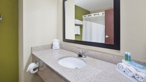 A bathroom with a sink, mirror, towel rack, and toiletries.