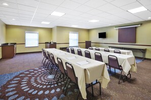 A conference room with a long table, chairs, a podium, a projector screen, and a carpeted floor. - Holiday Inn Express Circleville by IHG (Circleville)