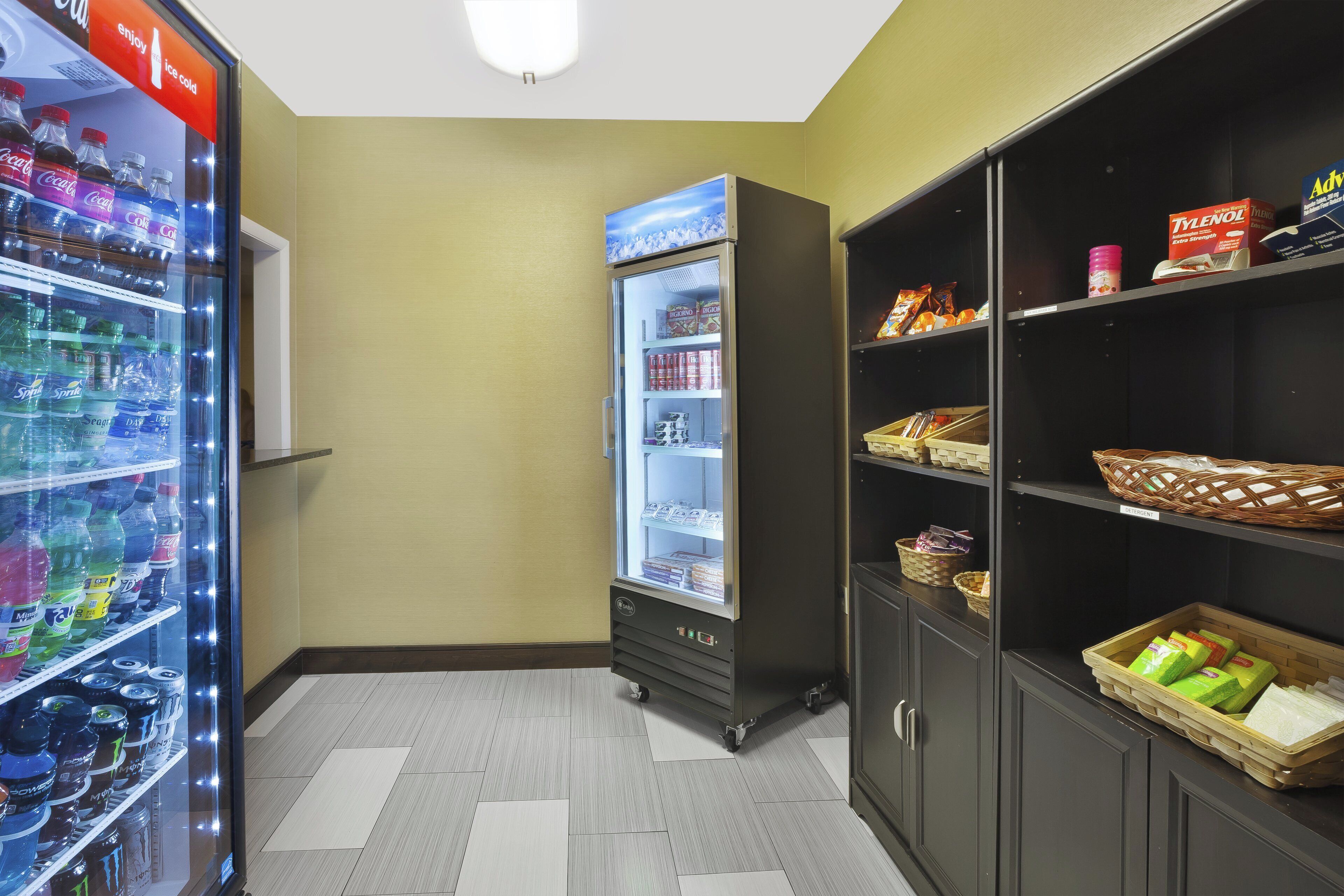 Un área de venta con diversas opciones de bebidas, una sección refrigerada y estantes llenos de aperitivos y artículos de aseo.