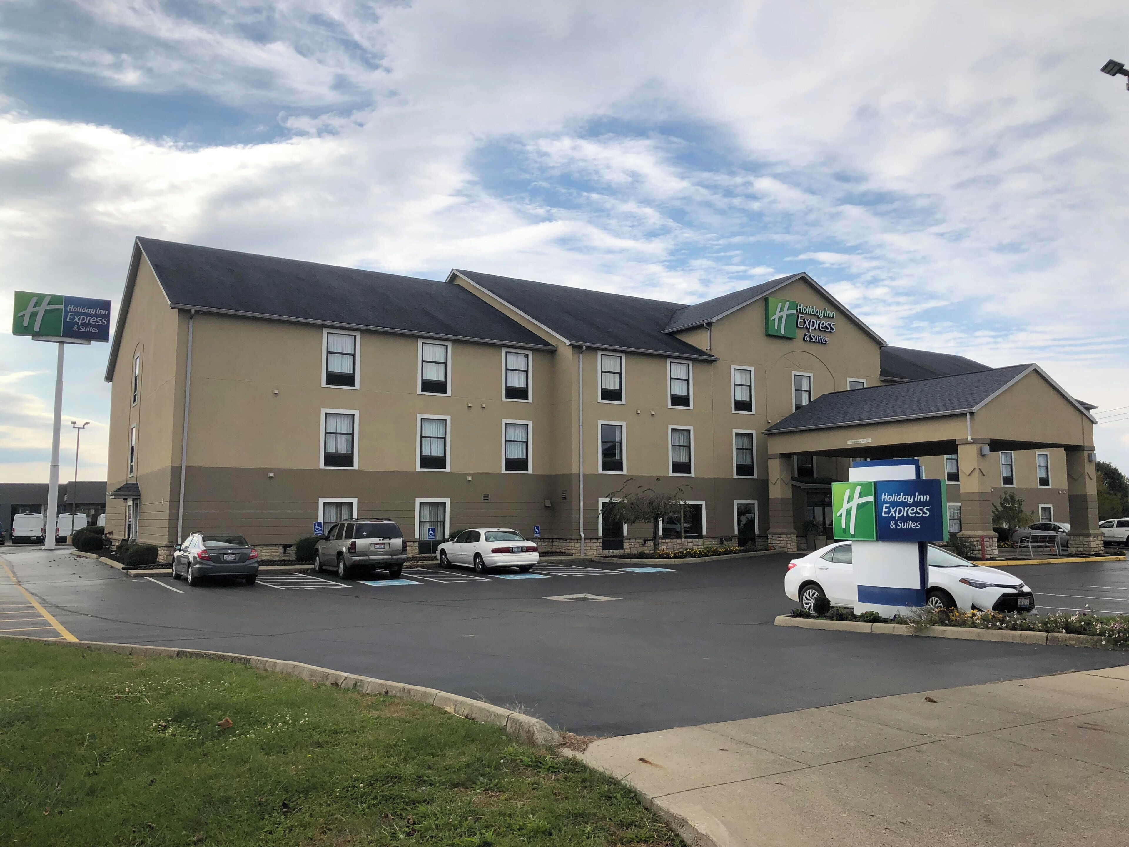 Un bâtiment de l’hôtel Holiday Inn Express avec un parking et quelques voitures.
