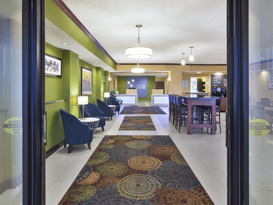 A hotel lobby with a central seating area, a reception desk, and a coffee bar.